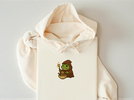 Embroidered Wizard Grog eating a bowl of ramen on a Comfort Colors Ivory Hoodie