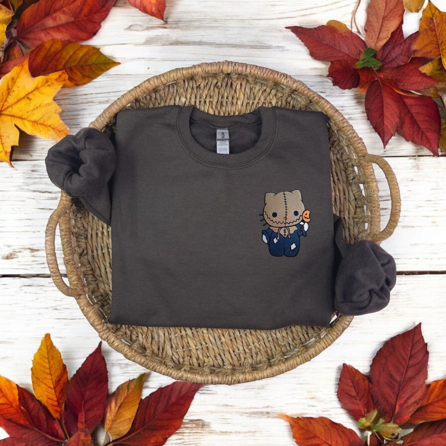 A black embroidered sweatshirt with a character from Hello Kitty dressed up as a Scarecrow