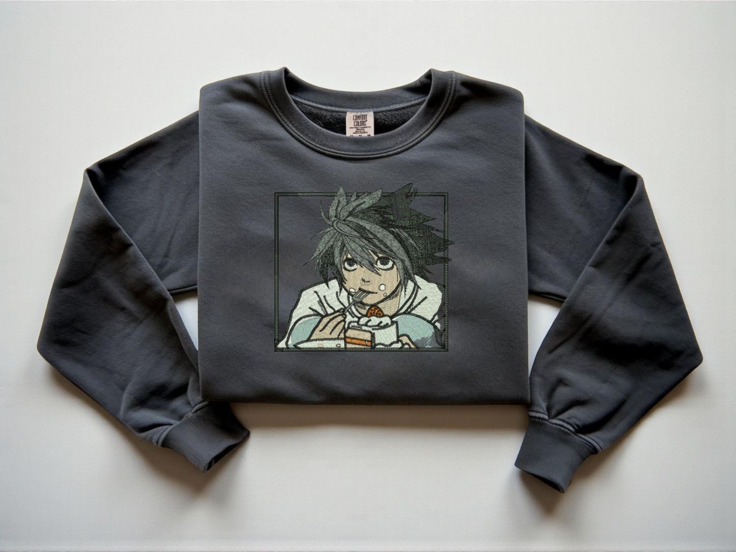 Pepper Comfort Colors crewneck sweatshirt with minimalist black line embroidery of L from Death Note crouching eating cake.