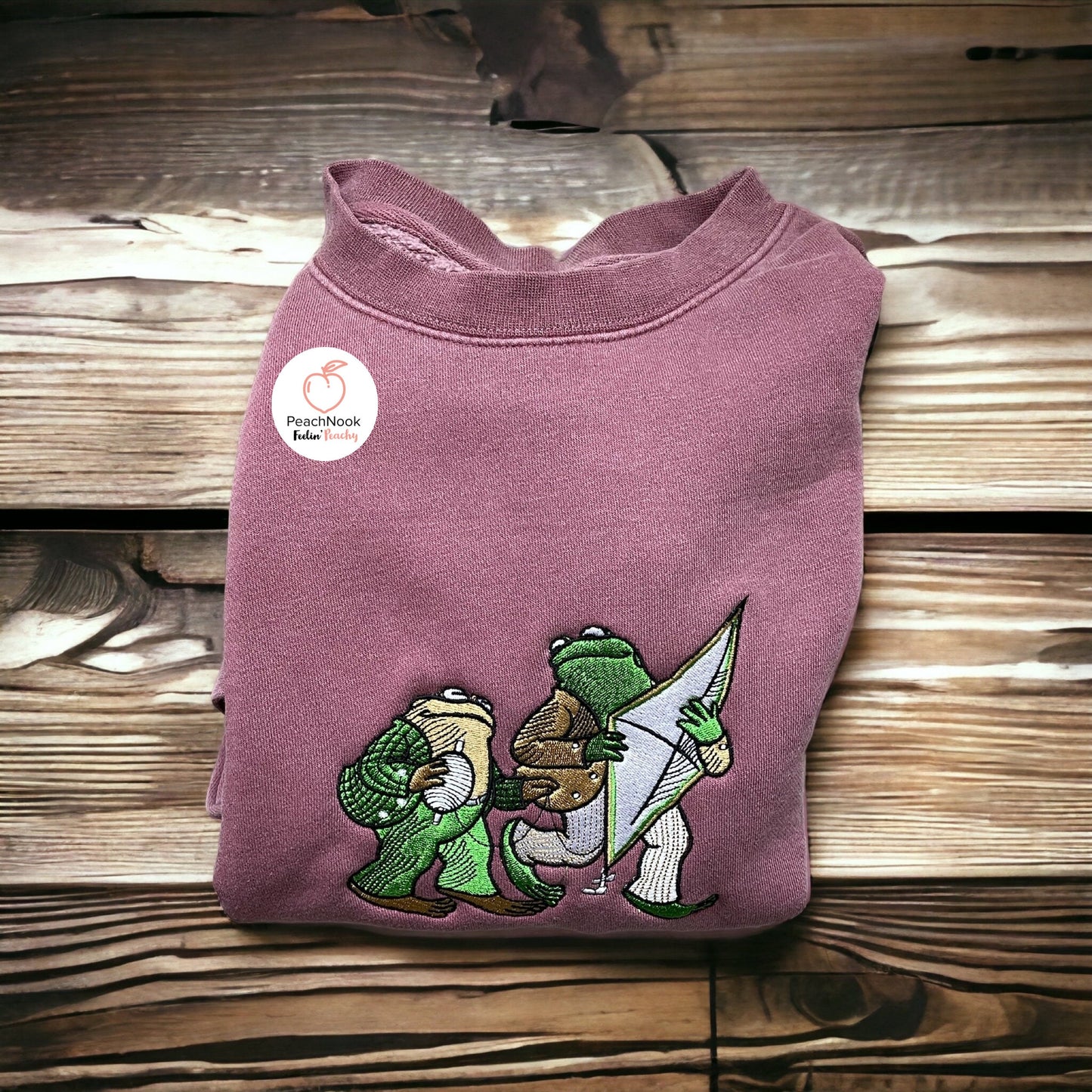Frog and Toad holding a Kite on an embroidered pink sweater