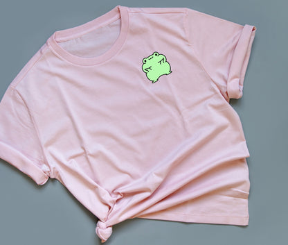 A Green Frog Holding his face up on a pink t-shirt.