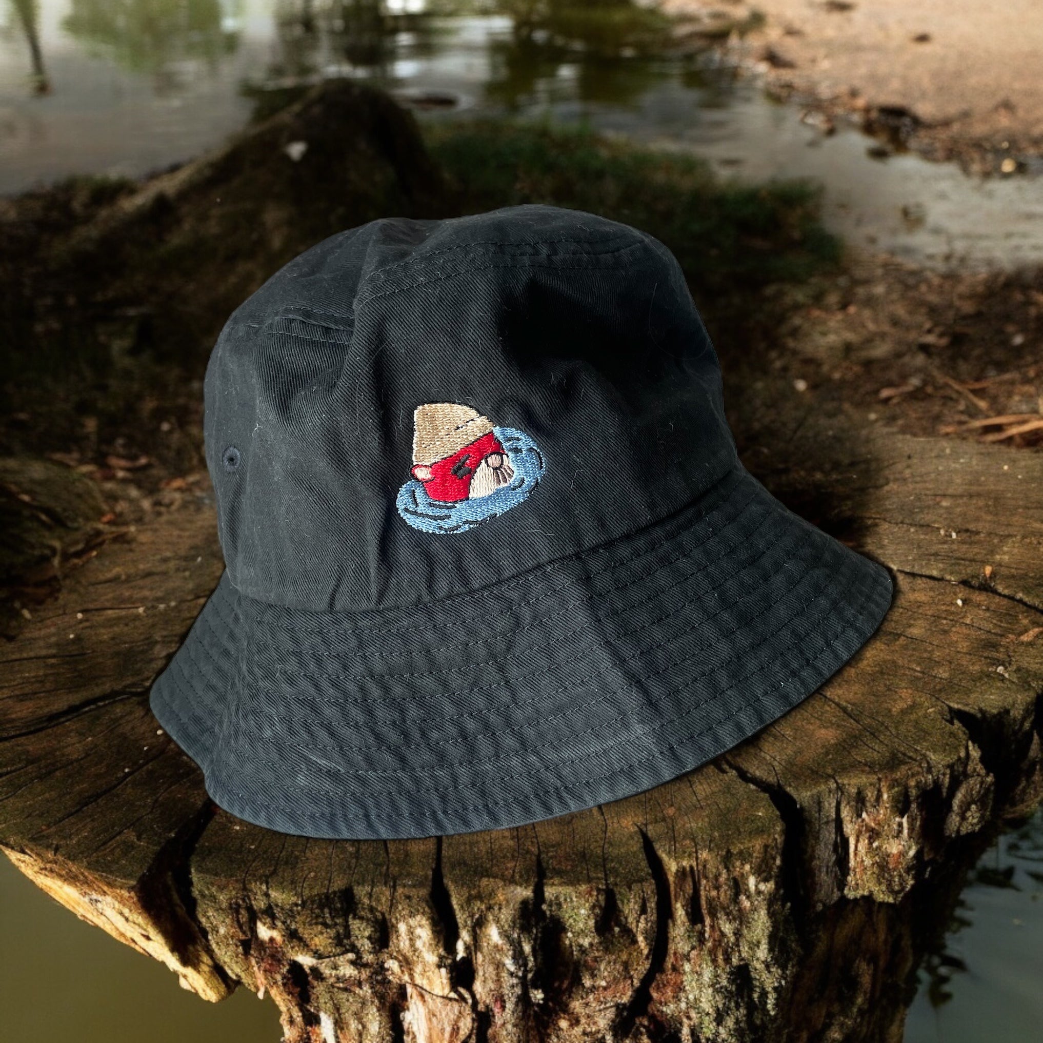 A black bucket hat with an embroidered animal crossing character, Carry Pascal, on the front 