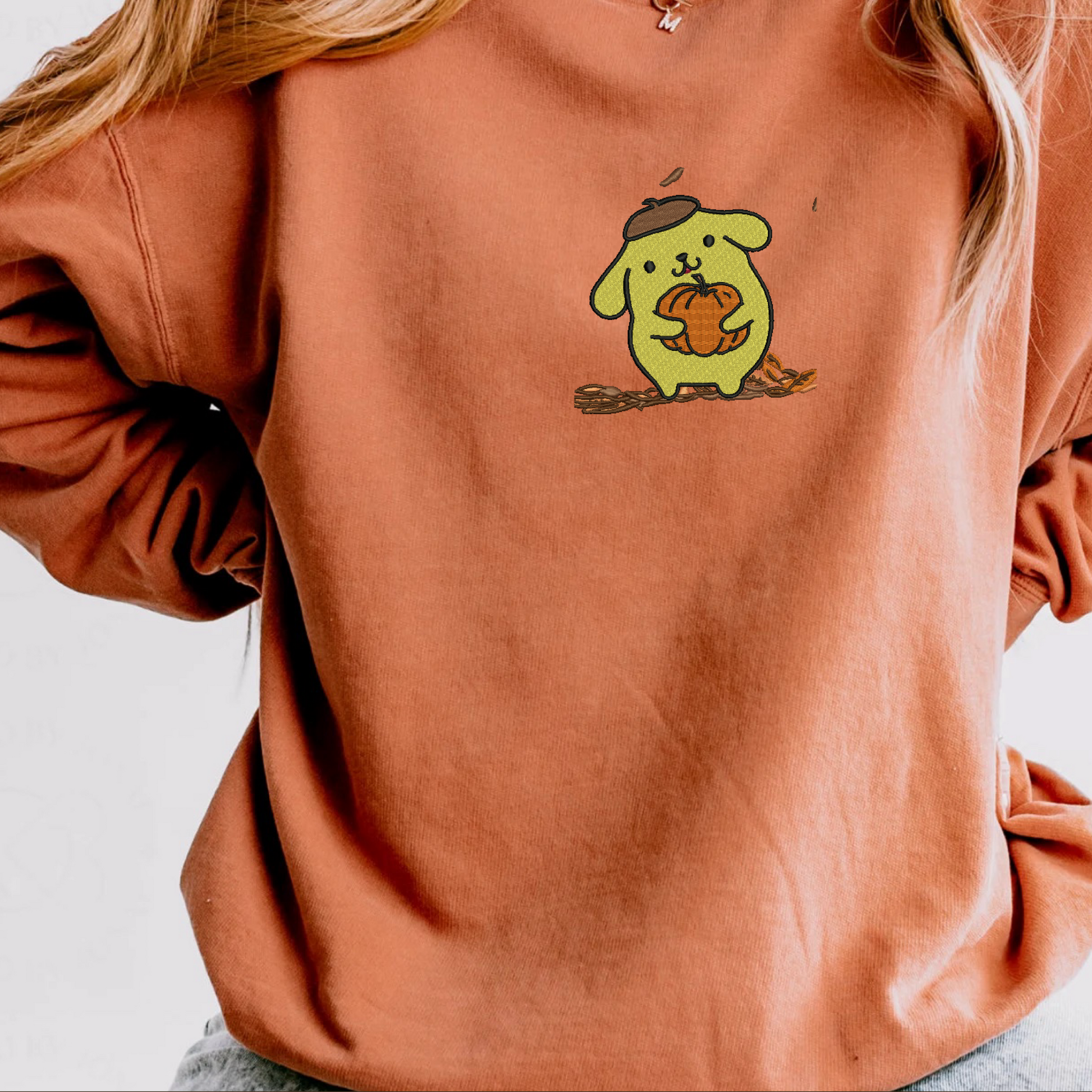 An orange sweatshirt with a cartoon animal character embroidered on the front named PomPom