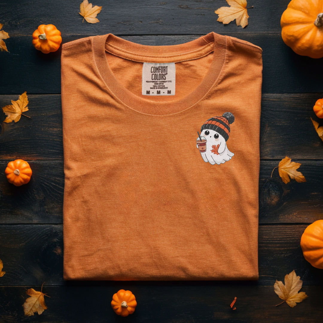 Orange t-shirt with a ghost design and pumpkins on a wooden surface