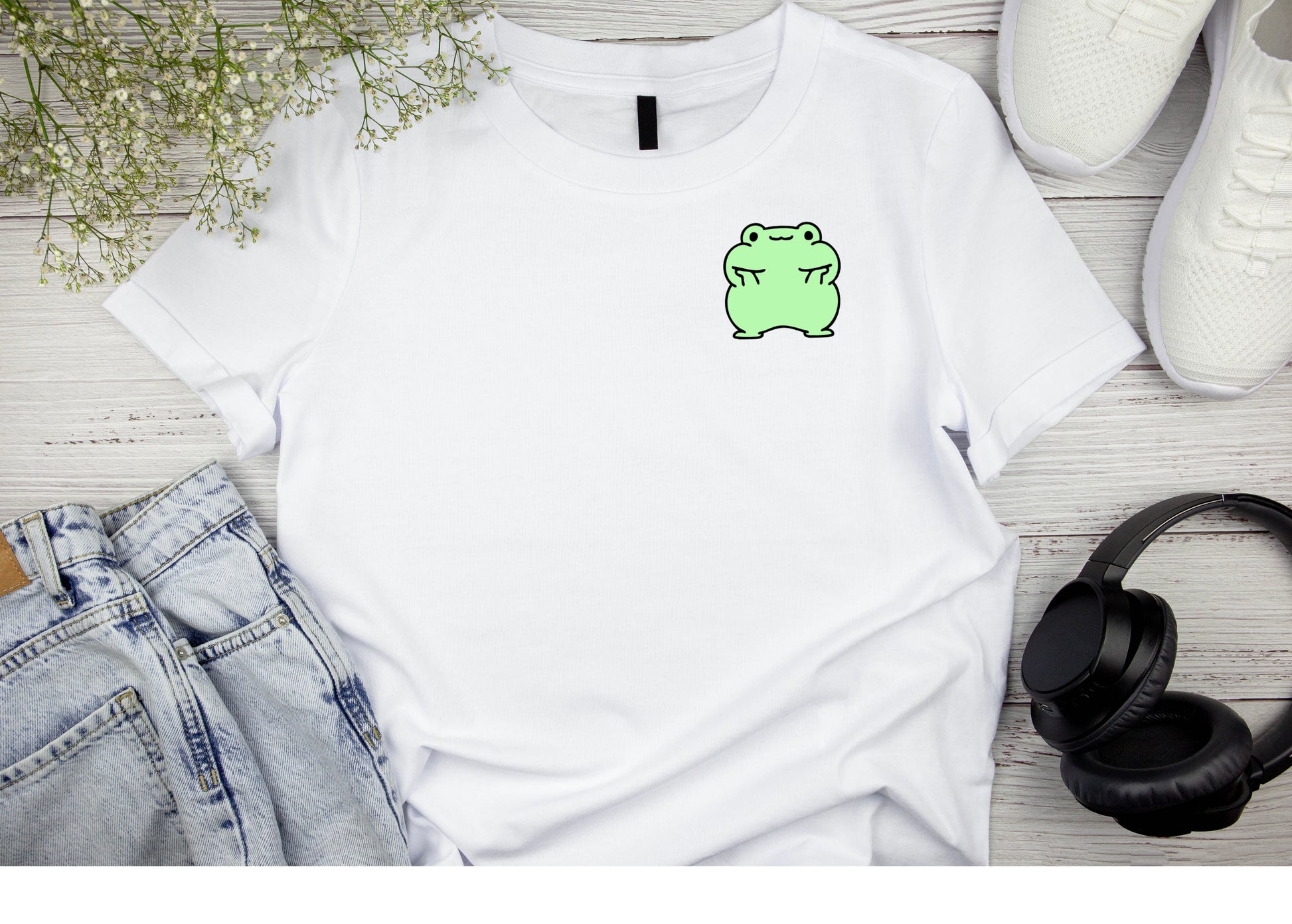 A Green Frog holding his cheeks up on a white clean T-shirt.