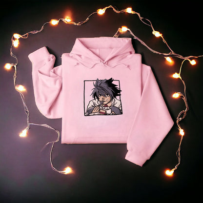 A character named L from the Anime Series, "Death Note' is on a pink embroidered hoodie eating cake. 