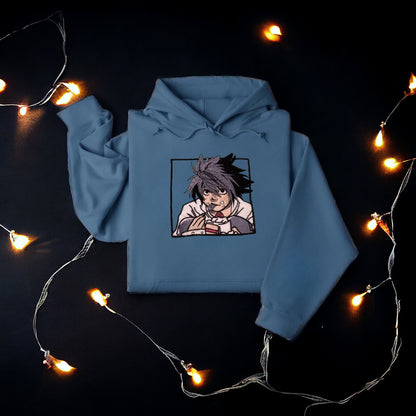 A character named L from the Anime Series, "Death Note' is on a blue embroidered hoodie eating cake. 