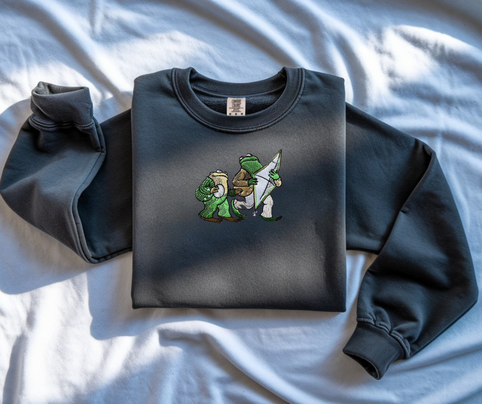 Pepper White Comfort Colors 1566 sweatshirt featuring detailed embroidery of Frog and Toad with a kite. Vintage bookish aesthetic crewneck.