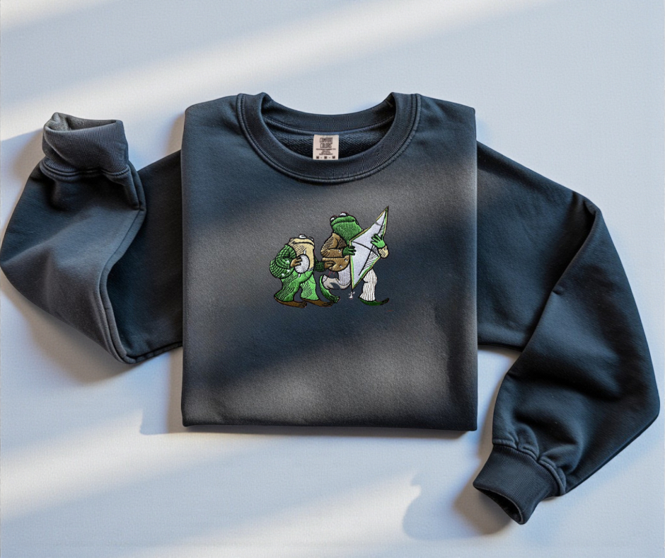 Pepper White Comfort Colors 1566 sweatshirt featuring detailed embroidery of Frog and Toad with a kite. Vintage bookish aesthetic crewneck.