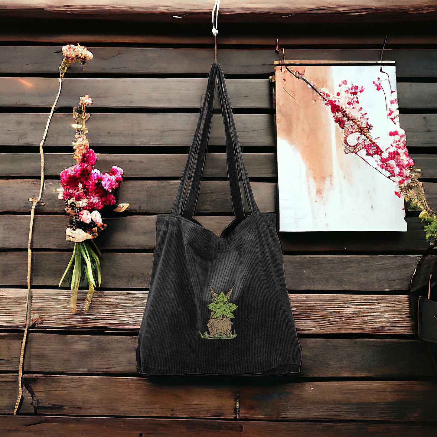 A Black Embroidered Tote bag that has a character from Zelda named Korok  