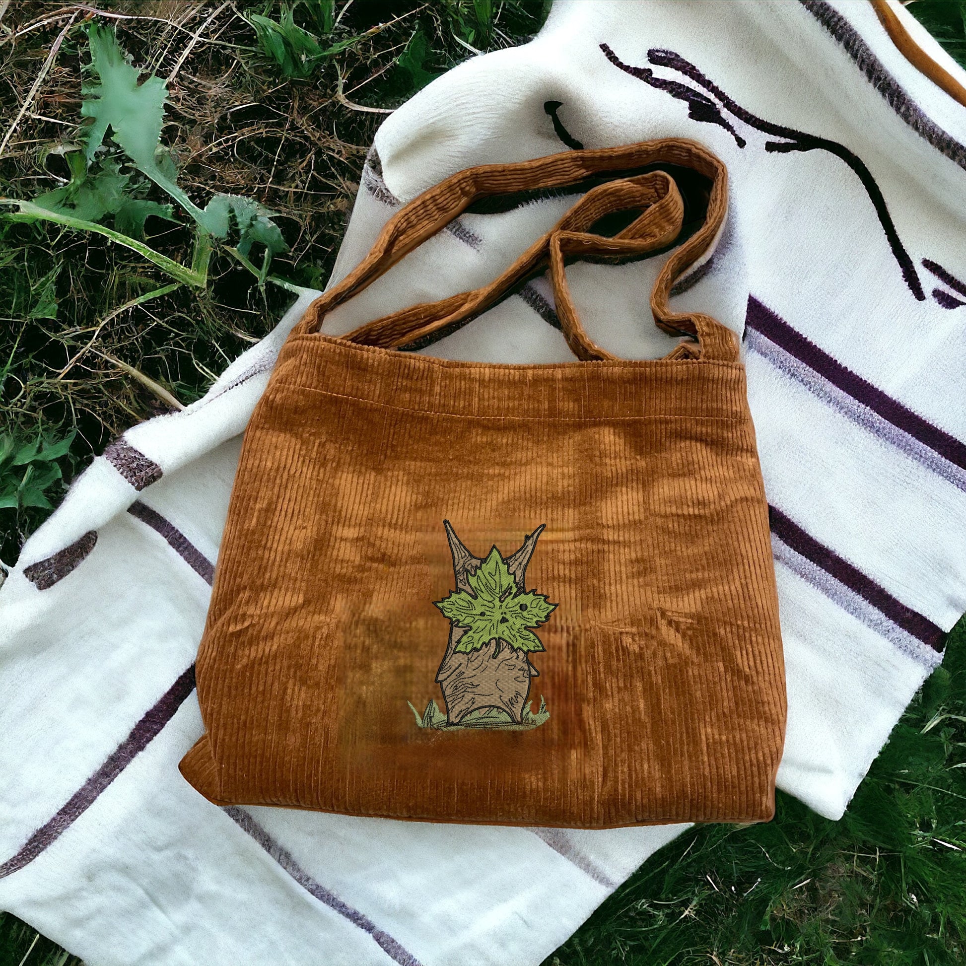 A Brown Embroidered Tote Bag that has a character from Zelda named Korok