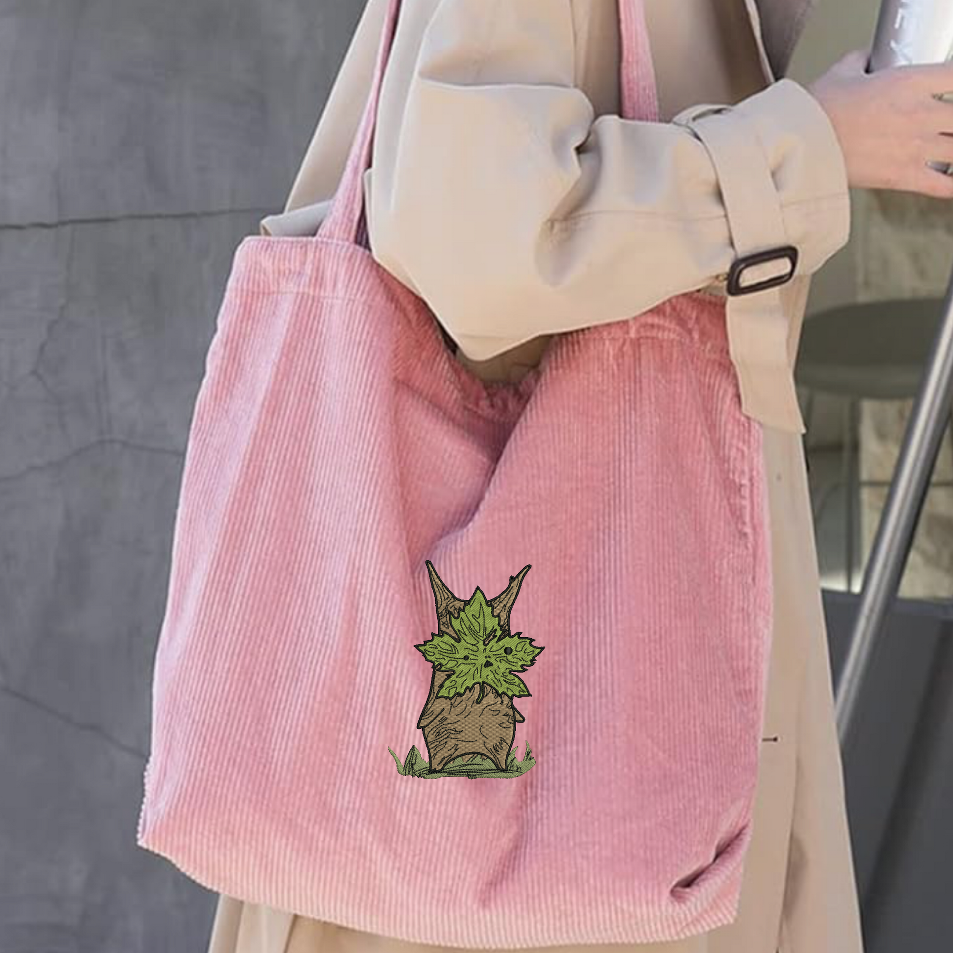A person carrying a pink embroidered tote bag featuring Korok from Zelda