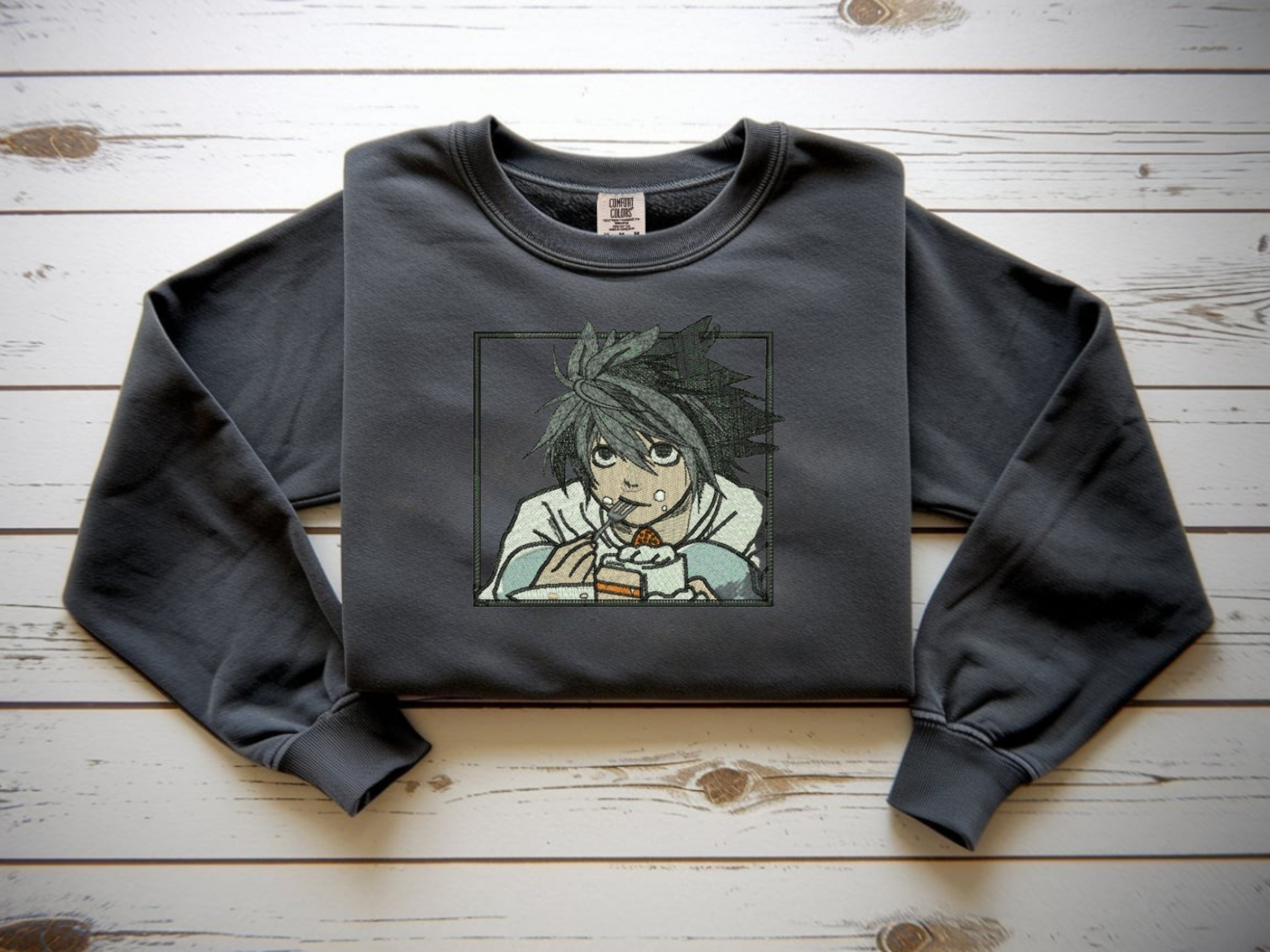 Pepper Comfort Colors crewneck sweatshirt with minimalist black line embroidery of L from Death Note crouching eating cake.