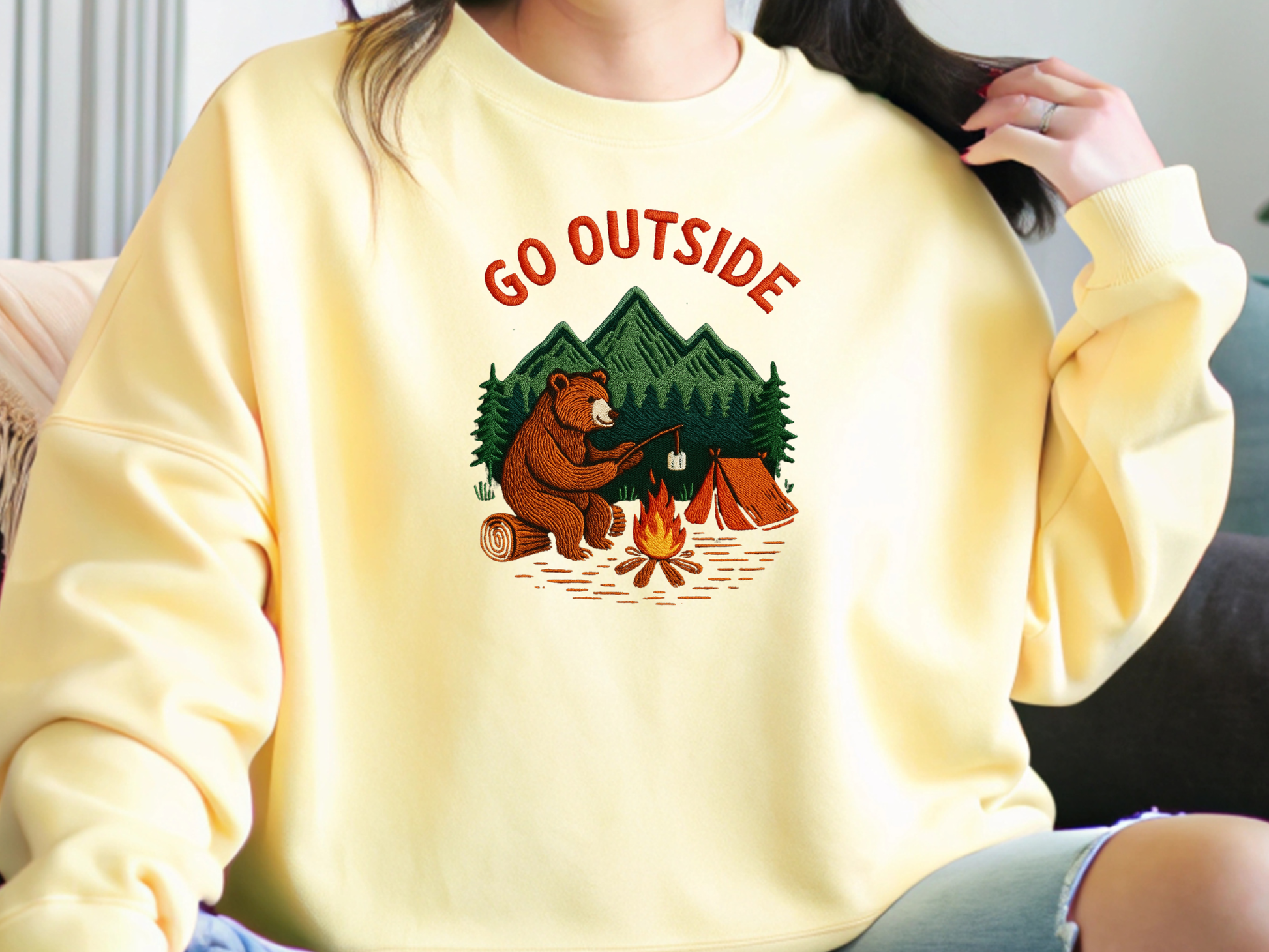 Camping bear embroidered crew neck sweatshirt featuring a bear roasting marshmallows by a campfire, cozy outdoor apparel for nature lovers.