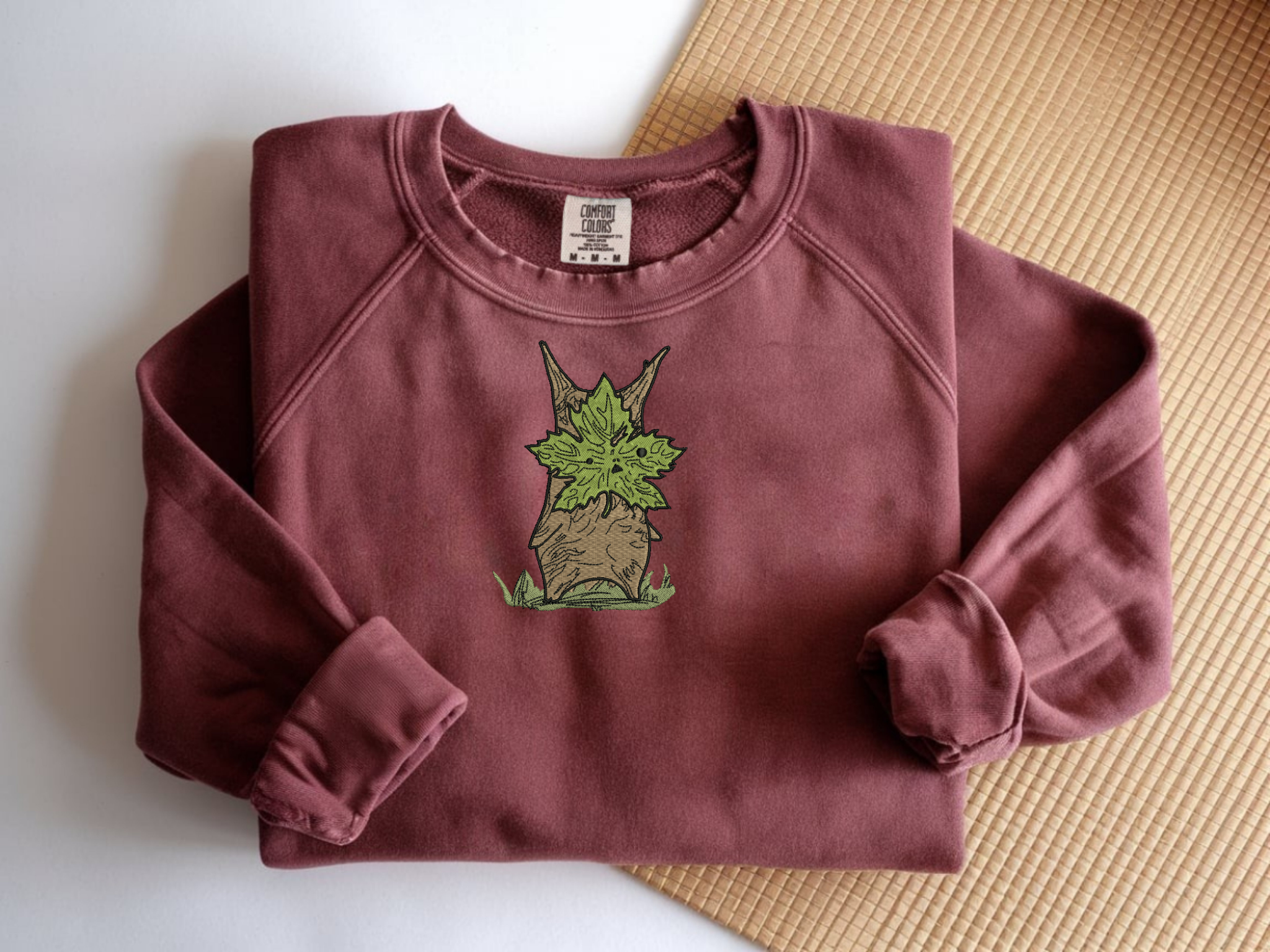 Embroidered Korok forest spirit on a Crimson Comfort Colors 1566 sweatshirt.