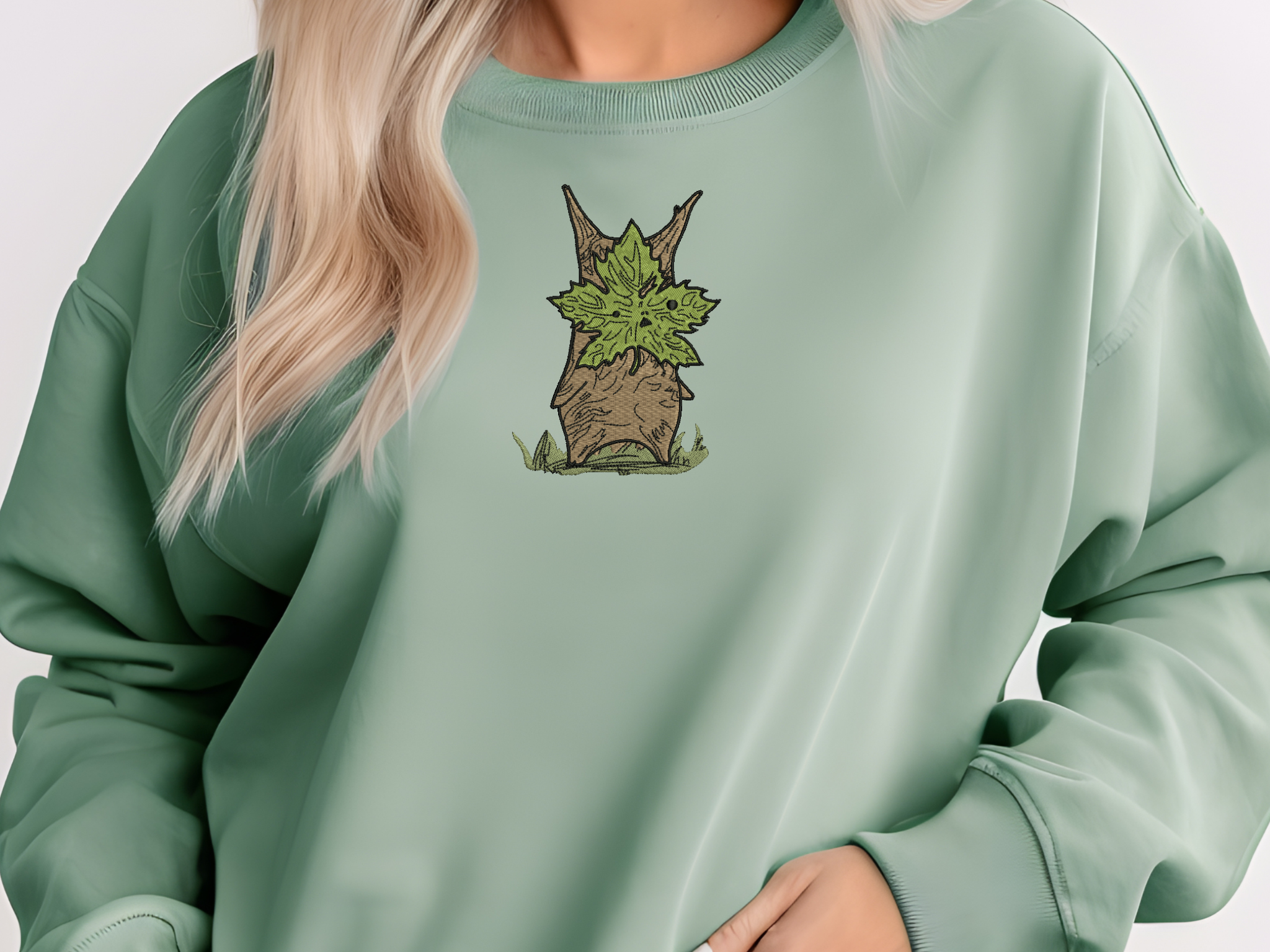 Person wearing a cozy, oversized Legend of Zelda inspired sweatshirt in an earthy light green color.