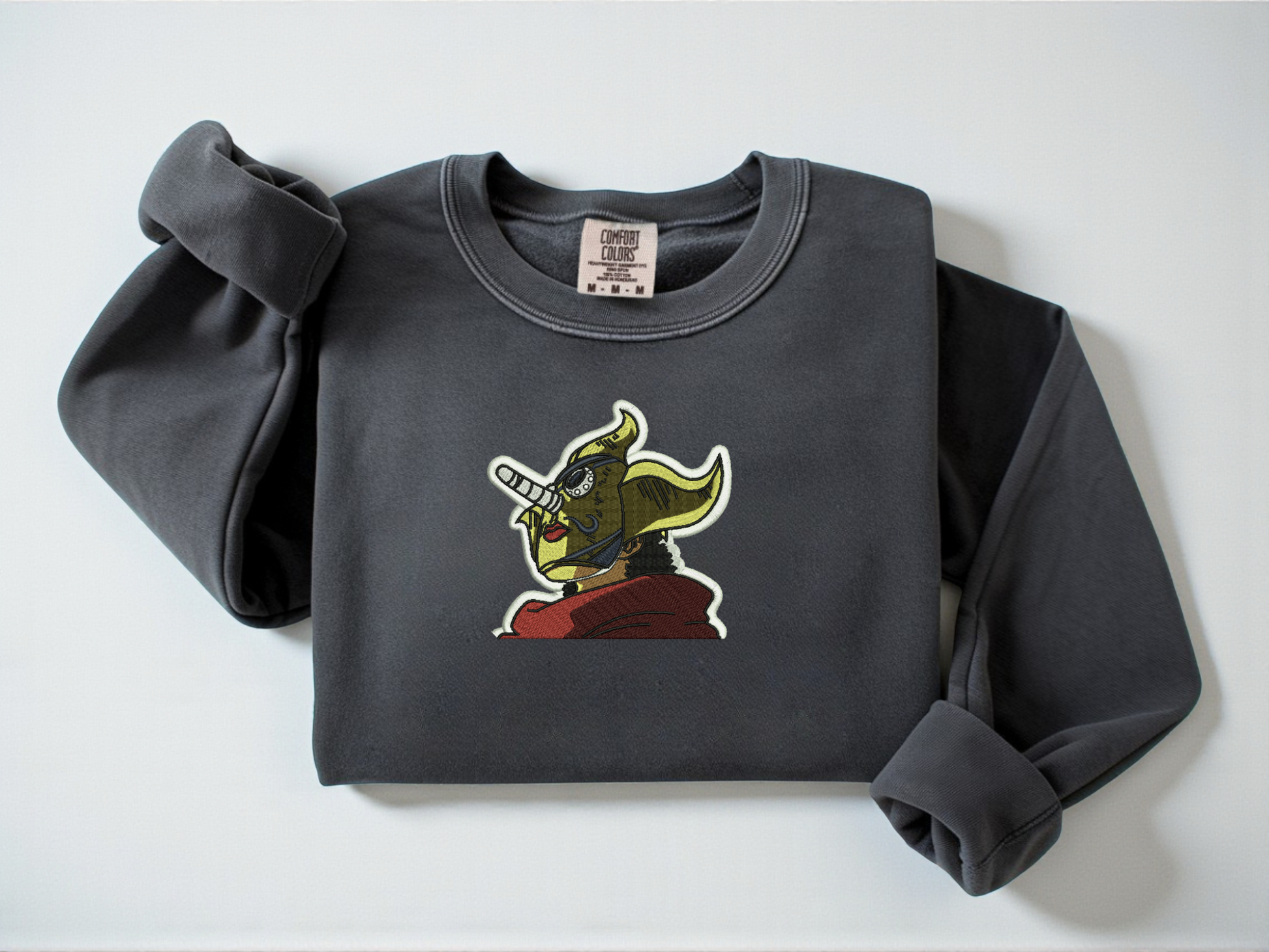 Embroidered Soge King One Piece On a Pepper Comfort Colors Crewneck with a white background.